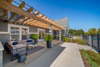 A patio area with a wooden pergola and seating area.